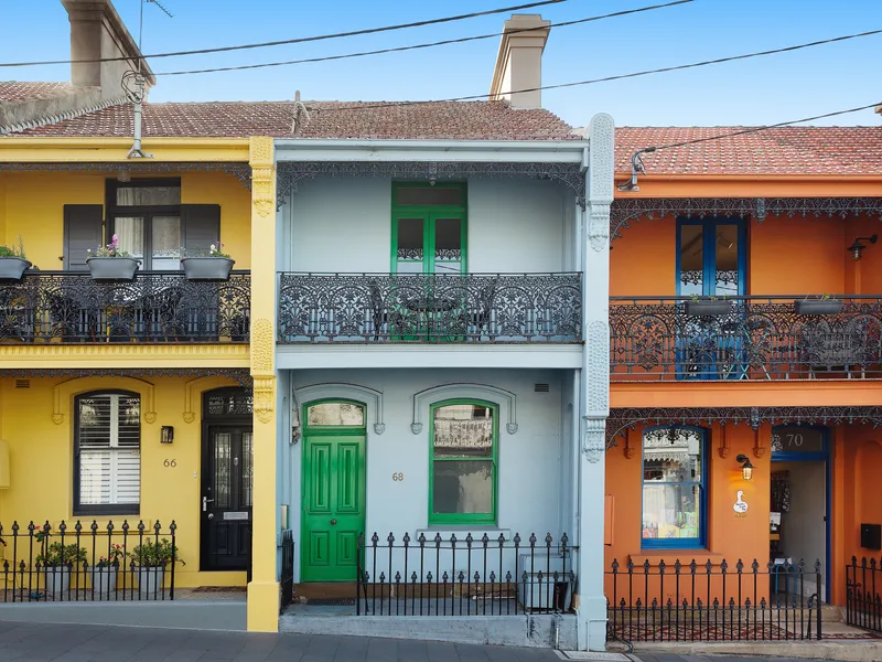 A row of colourful heritage Sydney terraces with wrought-iron balconies